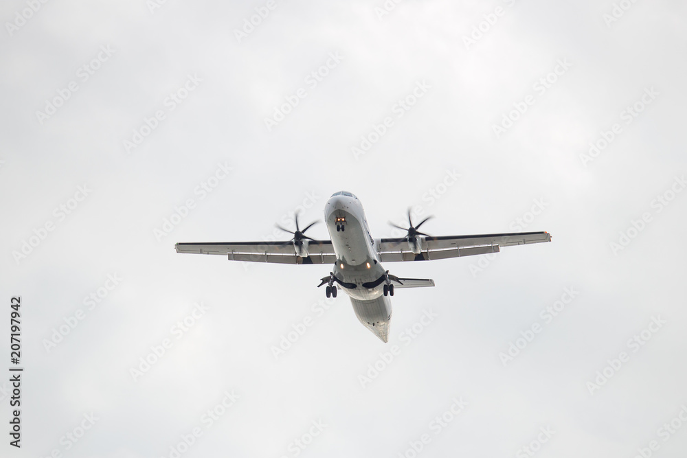 Fototapeta premium White airplane flying against a white sky