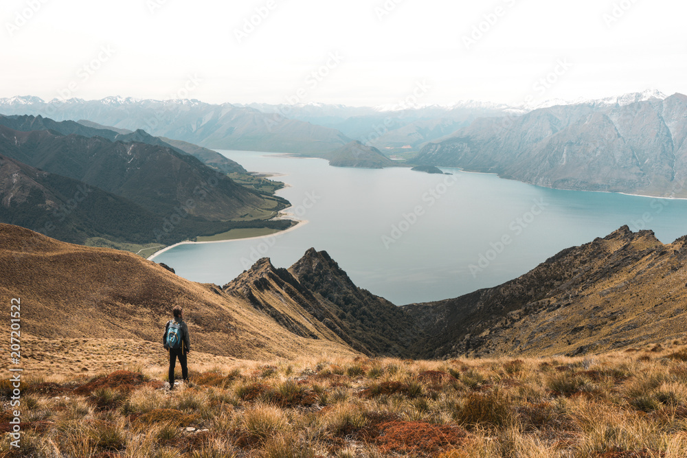 New Zealand, Isthmus peak: young man with Magnificent view of beautiful lake in rocky mountains