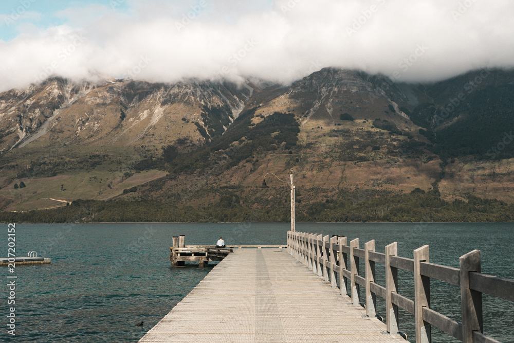 Obraz premium New Zealand, Glenorchy: photo of beautiful rocky mountains with blue lake and wooden bridge