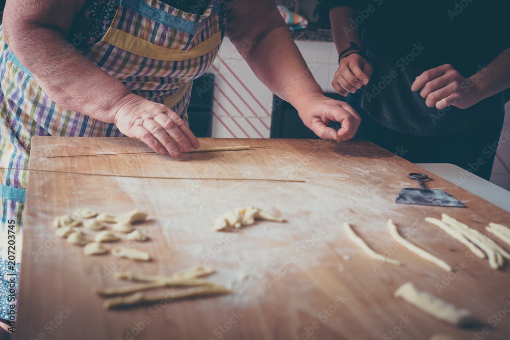 Process of production of pasta. woman hands make fresh pasta on wood board kitchen table