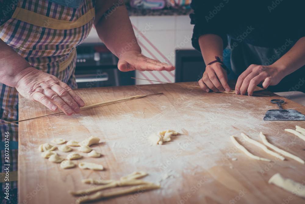 Process of production of pasta. woman hands make fresh pasta on wood board kitchen table