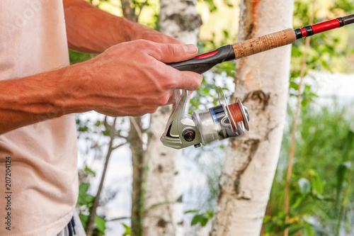 Fisherman hands with fishing rods is fishing against background of beautiful nature and lake or river. Camping tourism relax trip active lifestyle adventure concept