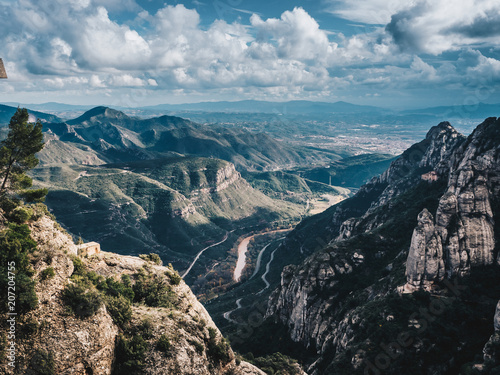 Aerial view of Montserrat mountains and river in a beautiful sunny summer day. Blue sky with clouds. Catalonia (near Barcelona), Spain © MagicalKrew