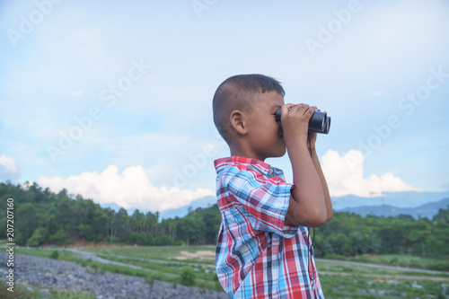 Cute little boy looking through binocular