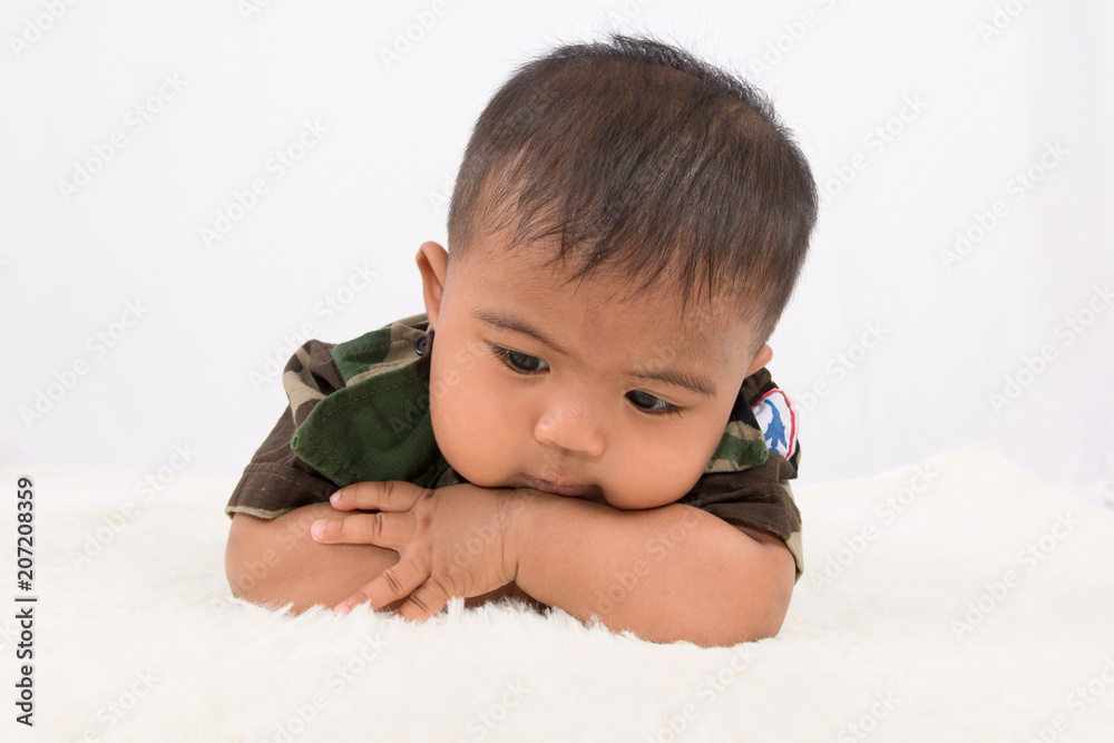 Cute little baby soldier in uniform lying on soft blanket Cute little baby soldier in uniform lying on soft blanket