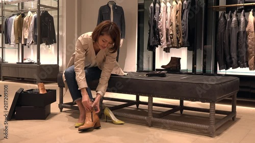 Asian people shopping for fashion goods and accessories. Japanese woman in luxury shop inside mall. Lady trying and buying new shoes in store