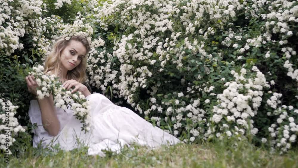 Beauty spring young woman enjoying nature in spring, Happy Beautiful girl in Garden with blooming trees. Smiling Model girl smelling blossom flowers Beauty spring young woman enjoying nature in spring, Happy Beautiful girl in Garden with blooming trees. Smiling Model girl smelling blossom flowers