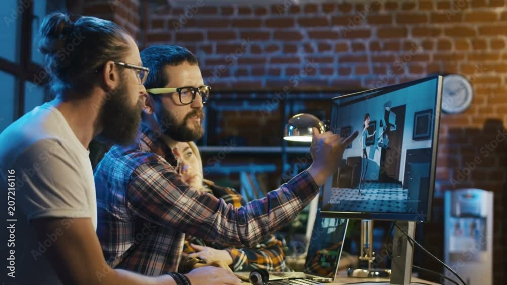 Side view of diverse group of people sitting at table with computer and coworking on creation of new cartoon
