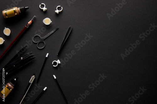 elevated view of scissors, pencil and brushes for permanent makeup isolated on black