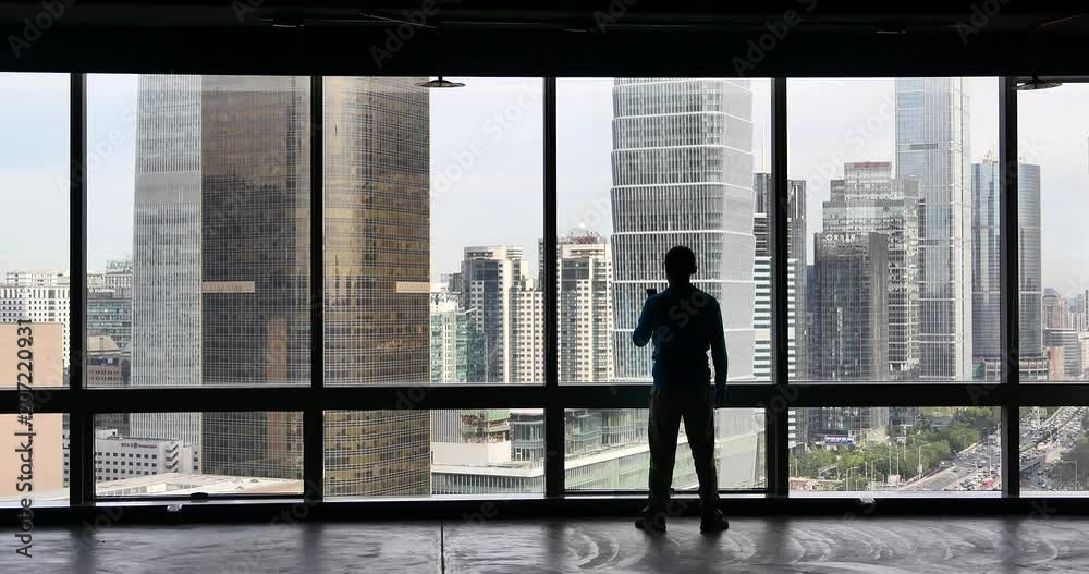 4k,businessman makes a phone call as overlooking the urban business building from window,skyscrapers,economic center. 4k,businessman makes a phone call as overlooking the urban business building from window,skyscrapers,economic center.