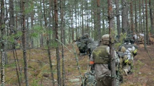 Soldiers in camouflage with combat weapons make their way outside the forest, with the aim of capturing it, the military concept photo