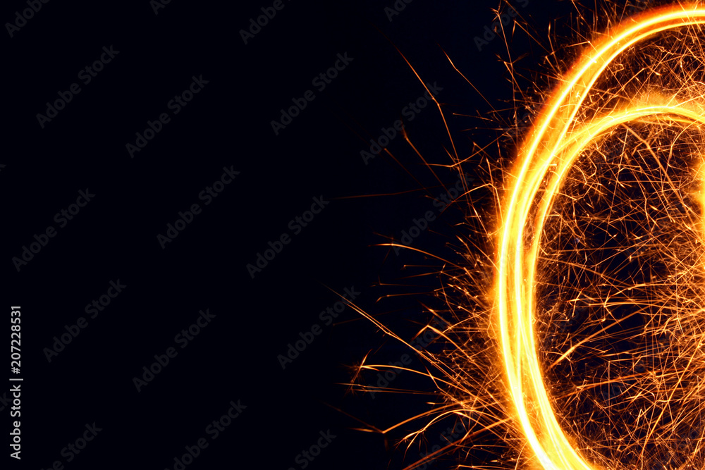 Sparkler background / A sparkler is a type of hand-held firework that burns slowly while emitting colored flames, sparks, and other effects.