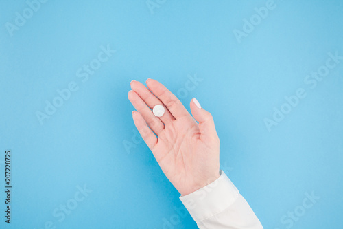 Female hand holding a white pill
