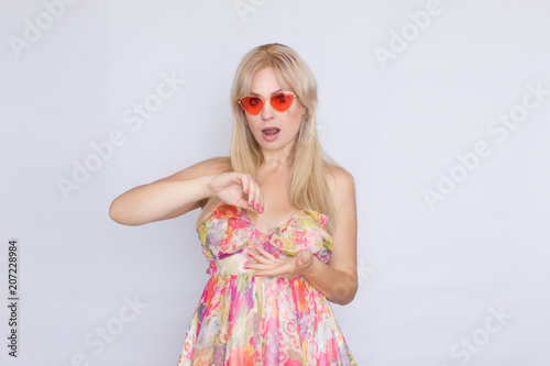 portrait of a young blond woman with long hair in a floral pink dress, and bright pink sunglasses
