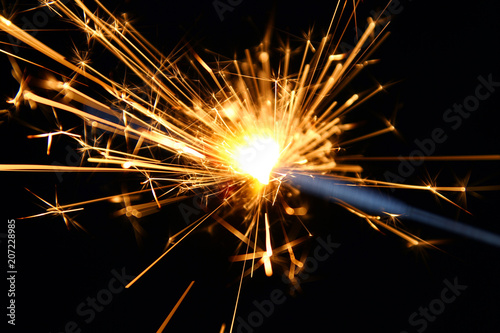 Sparkler background / A sparkler is a type of hand-held firework that burns slowly while emitting colored flames, sparks, and other effects.