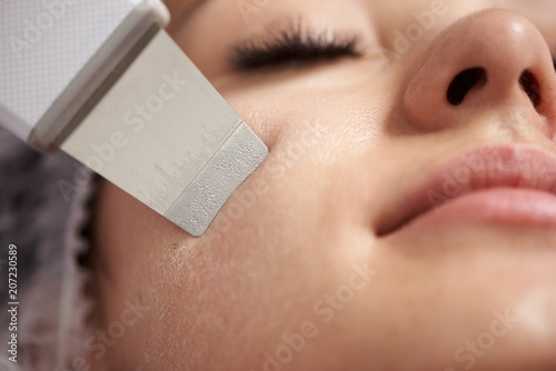 Closeup of an ultrasound facial peeling performed to young woman with false lashes photo
