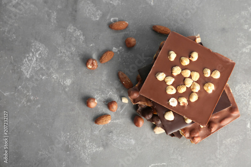 Delicious milk and dark chocolate bars with nuts on table, top view