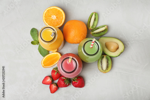 Flat lay composition with tasty juices and ingredients on grey background