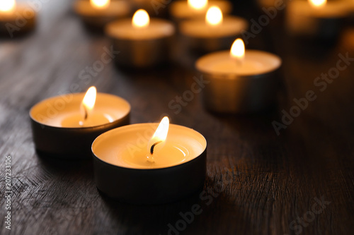 Wax candles burning on table in darkness  closeup