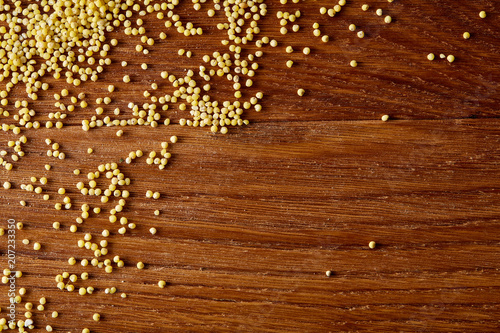 Pile of natural organic millet on rustic wooden background  top view  close-up  selective focus.