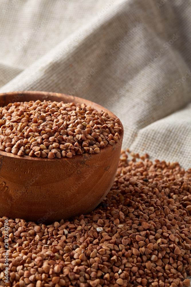 Bowl full of buckwheat grains on homespun tablecloth, close-up, selective focus, shallow depth of field. Bowl full of buckwheat grains on homespun tablecloth, close-up, selective focus, shallow depth of field.