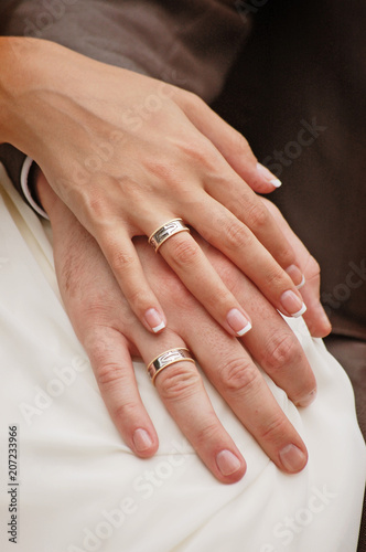 The bride and groom hold hands together with rings