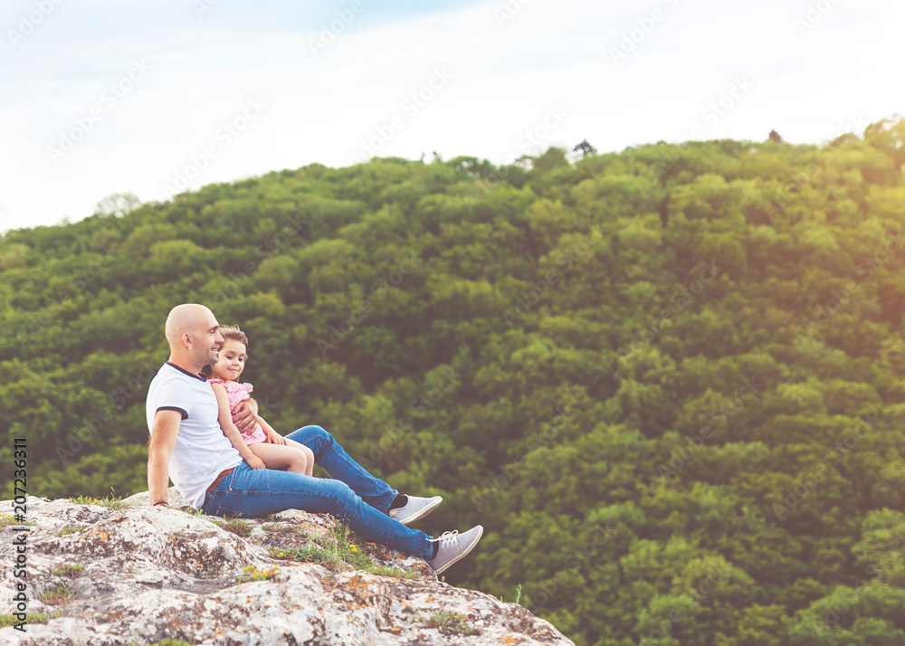 Father and daughter sitting on the mountain rock
