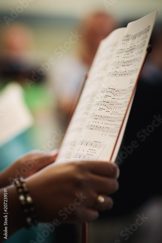 Canvas-taulu A woman sings in a choir and holds her sheet music notes