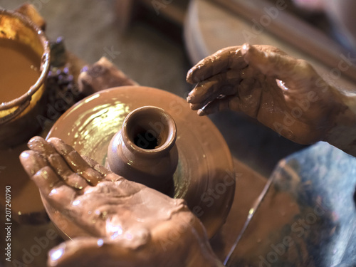 Professional male potter making ceramics on potter's wheel in workshop, studio. Close up shot of potter's hands. Handmade, art and handicraft concept