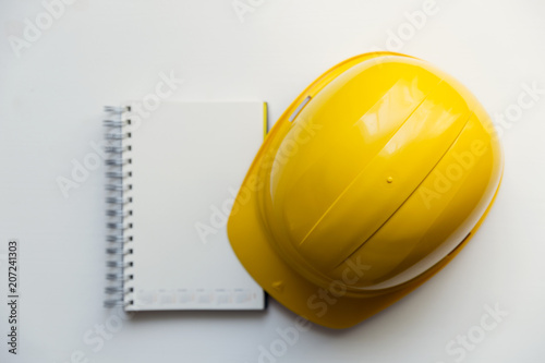 Yellow safety helmet and notebook isolated on white background. Construction and safety concept