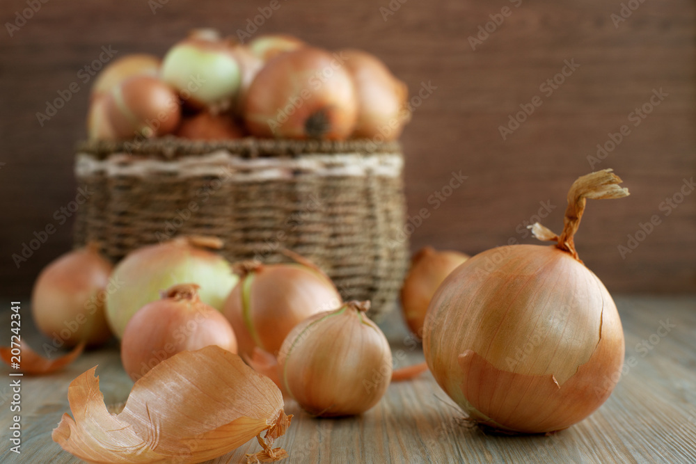 Large onions in a basket. Harvest of onions in a wicker basket on a wooden background. A lot of vegetables for a healthy diet.