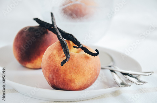 Peach and vanilla pod as food ingredients for dessert cooking. Close up, white background.