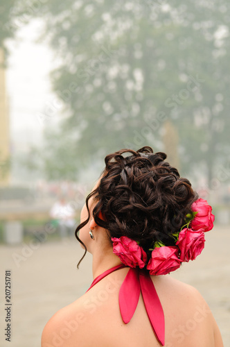Girl with a hairstyle decorated with fresh red roses.