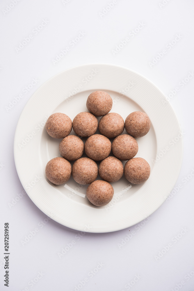 Nachni laddu or Ragi laddoo or balls made using finger millet, sugar and ghee. It's a healthy food from India. Served in a bowl or plate over moody background. Selective focus Nachni laddu or Ragi laddoo or balls made using finger millet, sugar and ghee. It's a healthy food from India. Served in a bowl or plate over moody background. Selective focus