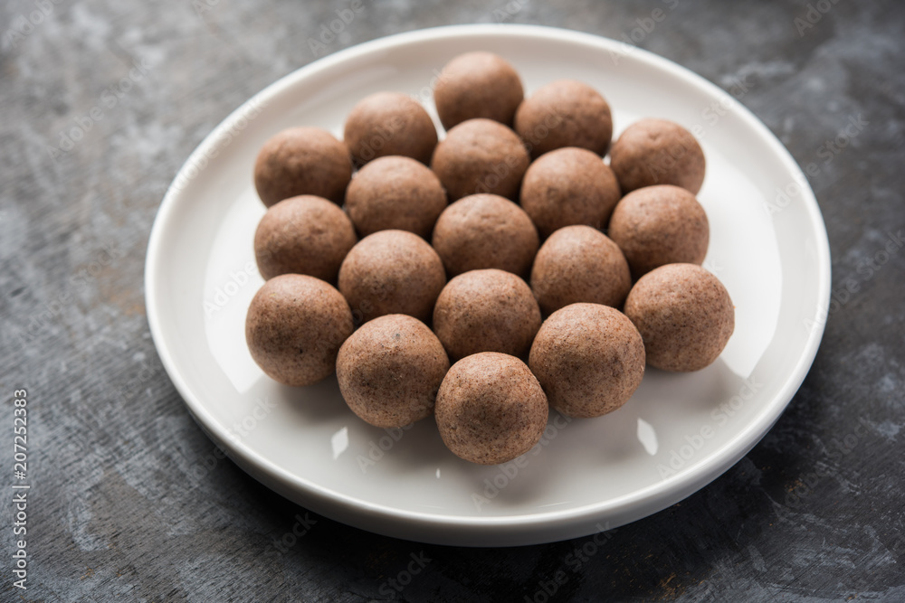 Nachni laddu or Ragi laddoo or balls made using finger millet, sugar and ghee. It's a healthy food from India. Served in a bowl or plate over moody background. Selective focus Nachni laddu or Ragi laddoo or balls made using finger millet, sugar and ghee. It's a healthy food from India. Served in a bowl or plate over moody background. Selective focus