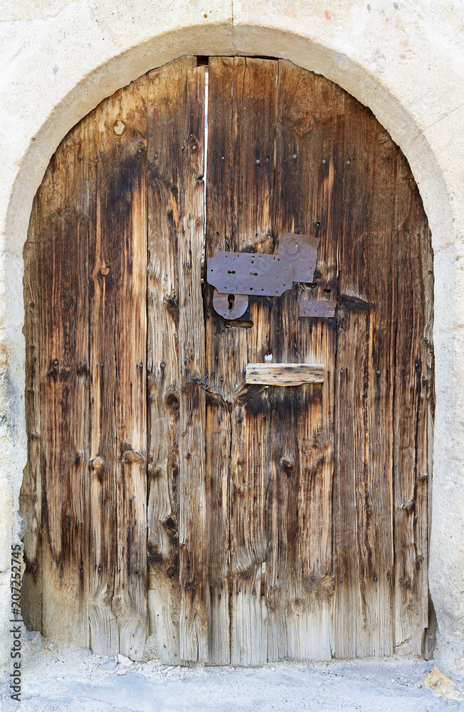 Ancient arched antique wooden doors with a metal lock in the middle