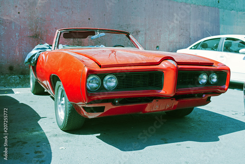 A red American vintage classic convertible car parked in a  repair shop in the street of Istanbul