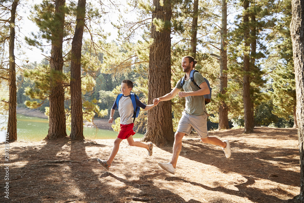 Father And Son On Hiking Adventure Running Through Forest Father And Son On Hiking Adventure Running Through Forest