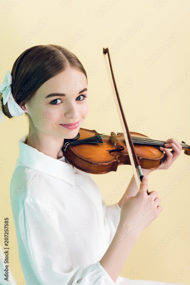 attractive teen girl playing violin, isolated on yellow attractive teen girl playing violin, isolated on yellow