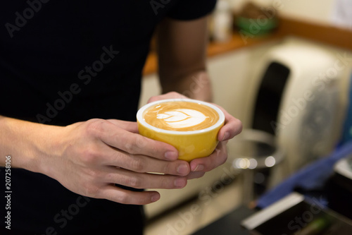 Barista man holding cup of coffee.