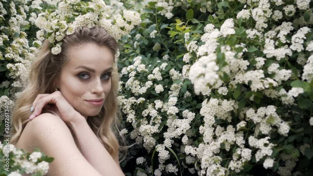 Beauty spring young woman enjoying nature in spring, Happy Beautiful girl in Garden with blooming trees. Smiling Model girl smelling blossom flowers Beauty spring young woman enjoying nature in spring, Happy Beautiful girl in Garden with blooming trees. Smiling Model girl smelling blossom flowers