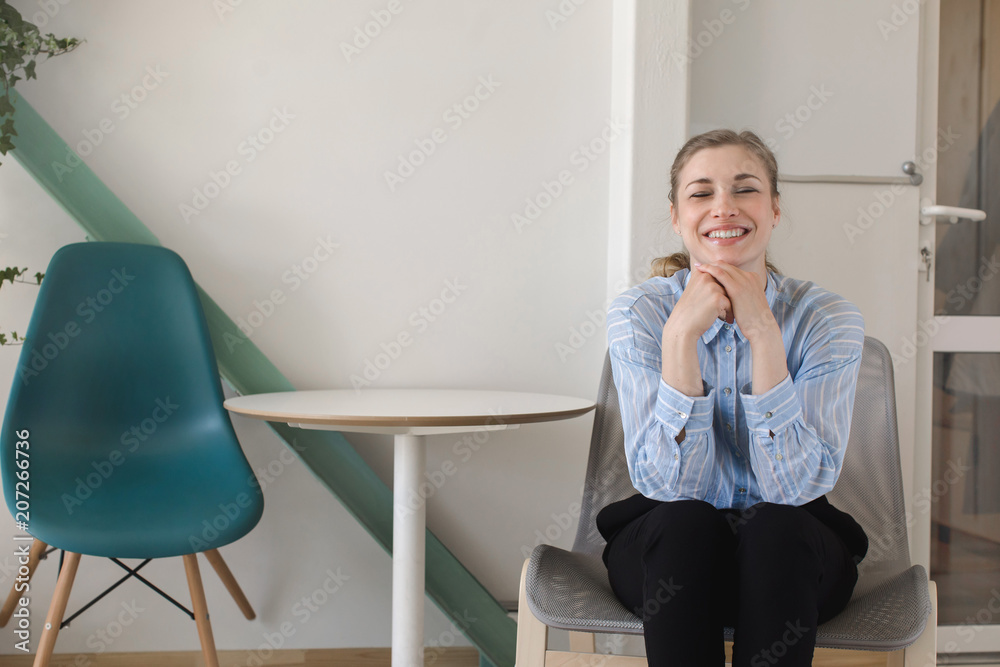 Crop view of attractive female with close eyes sitting on chair and smiling Crop view of attractive female with close eyes sitting on chair and smiling