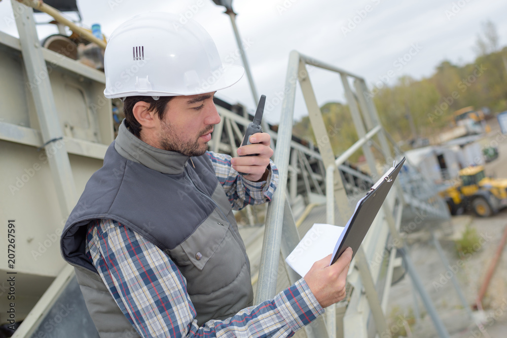 Man on construction site giving instructions on walkie talkie foto de Stock  | Adobe Stock