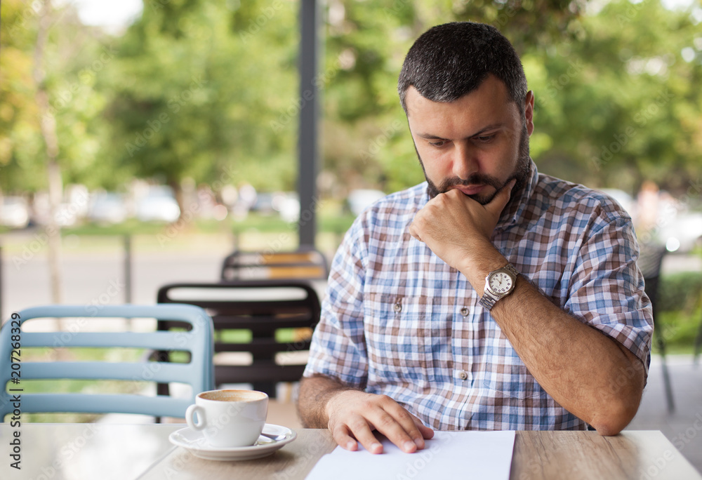 Worried man looking at paper in cafe Worried man looking at paper in cafe