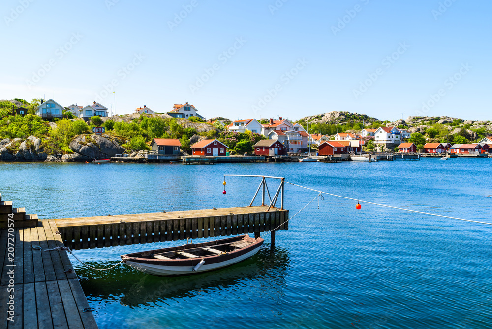 The coastal village of Storkalv, seen from across the sound Kalvesund outside Ronnang on Tjorn, Sweden. Small rowboat tied to a pier in the foreground.