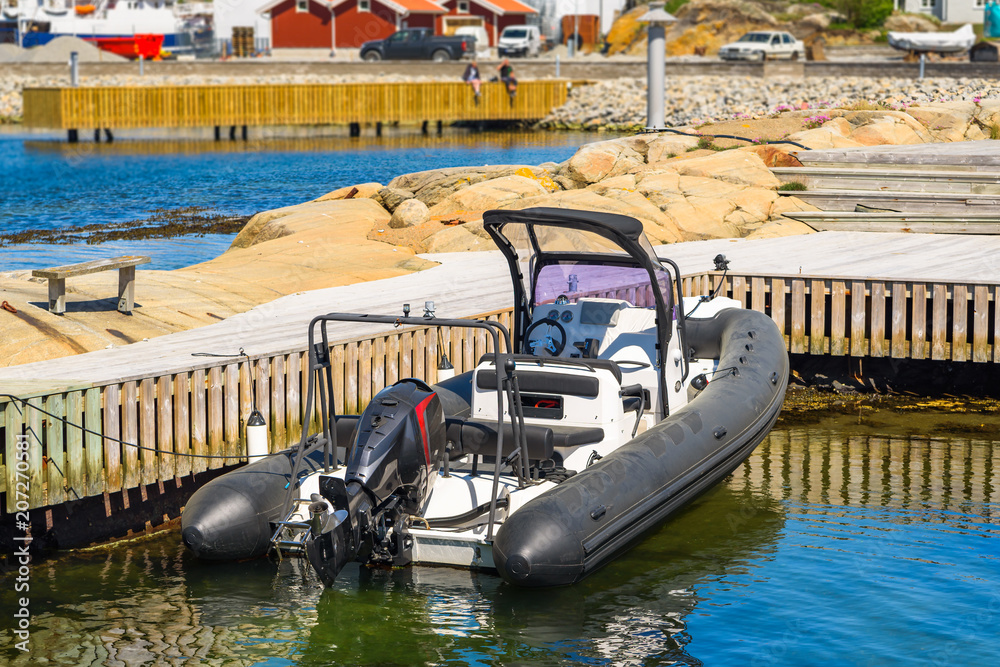 Black and white RIB, rigid inflatable boat, anchored beside a pier ...