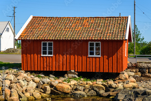 Red wooden fishing shed on the rocks. Stacks of rocks hold the building level and off the ground.