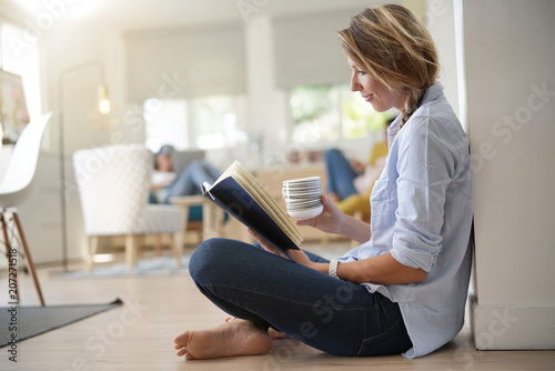 Beautiful 30-year-old woman relaxing with book and hot tea
