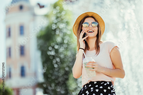 Smiling young woman teenager talking phone on summer street drinking mojito outdoor sunlight photo