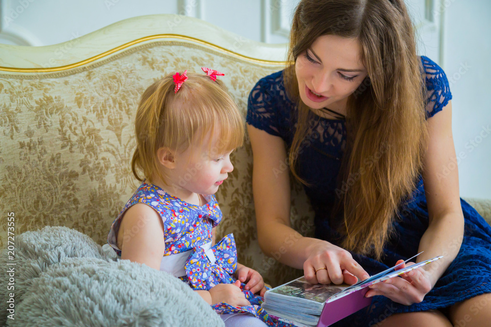 Young mother and her baby daughter looking photobook togerher at home. Family, childhood and leisure concept Young mother and her baby daughter looking photobook togerher at home. Family, childhood and leisure concept